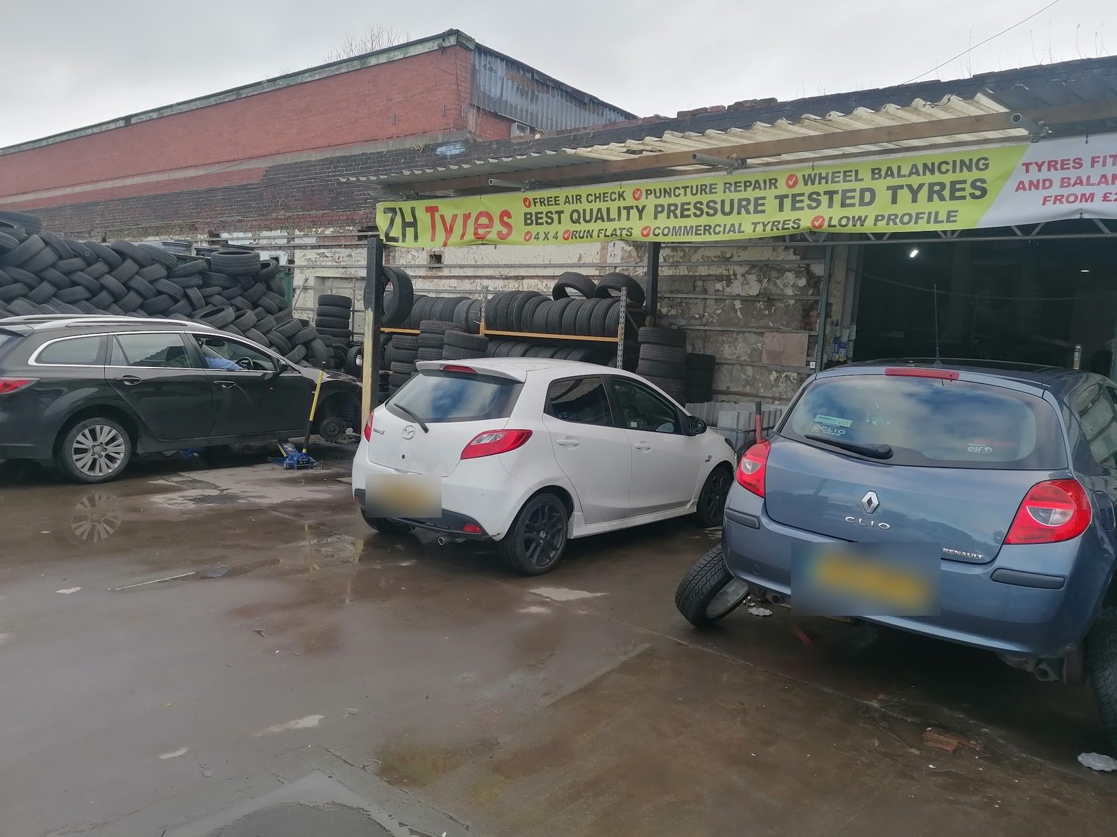 The ZH Tyres yard on Hargher Street with the yellow banner over the fitting bays and cars in for tyres