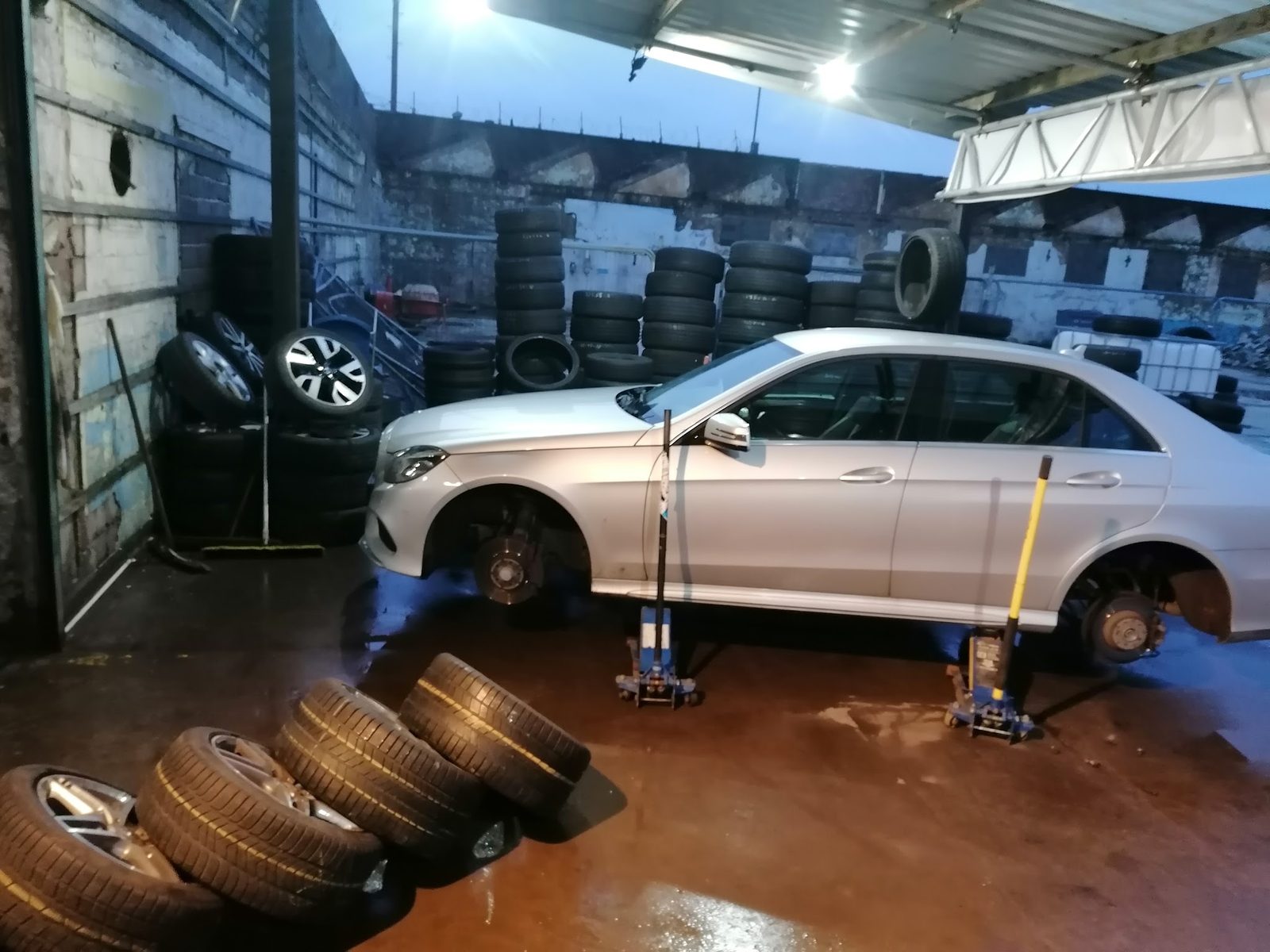 A silver Mercedes up on jacks in the ZH Tyres fitting bay with its wheels off