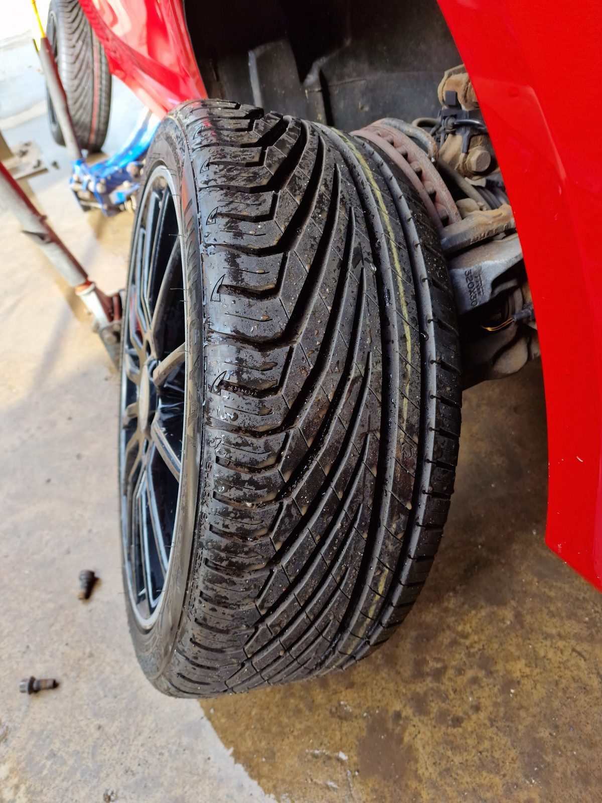 A freshly fitted tyre on a red car in the ZH Tyres workshop