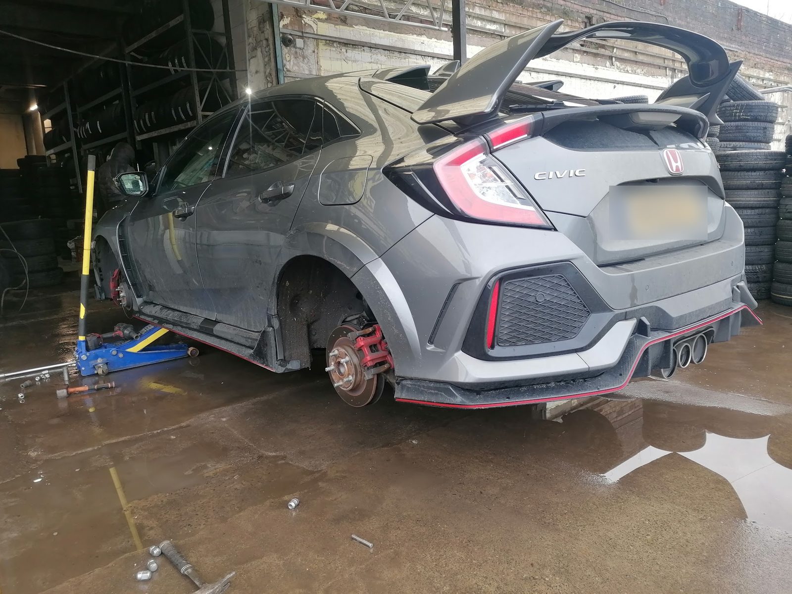 A grey Honda Civic Type R on a trolley jack inside the ZH Tyres workshop